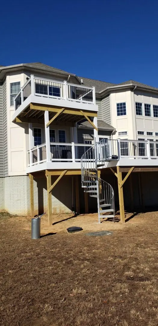 A spiral staircase leads to a deck on a house's exterior.