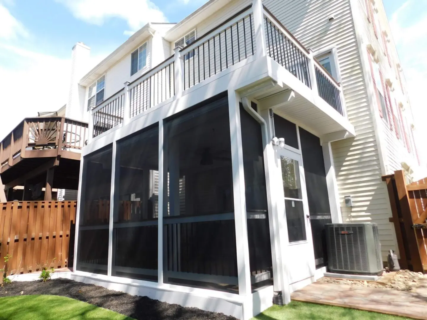 Screened-in porch attached to a two-story house with white railing.