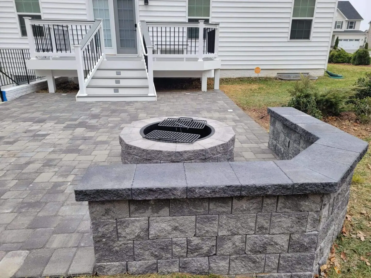 Stone fire pit with seating area on a paved patio.