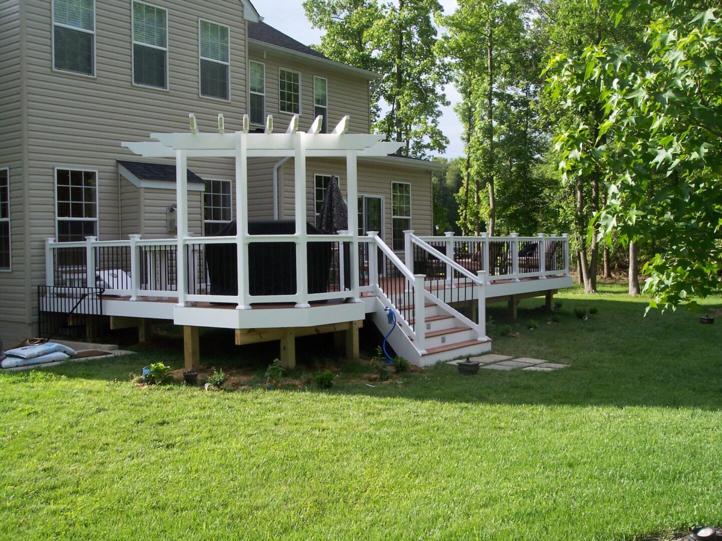 A backyard deck with a white pergola